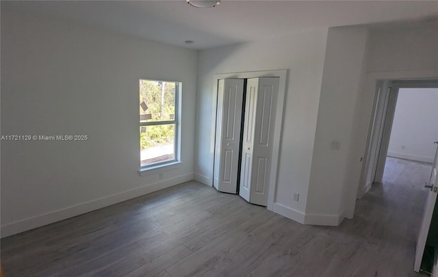 unfurnished bedroom featuring wood-type flooring and a closet