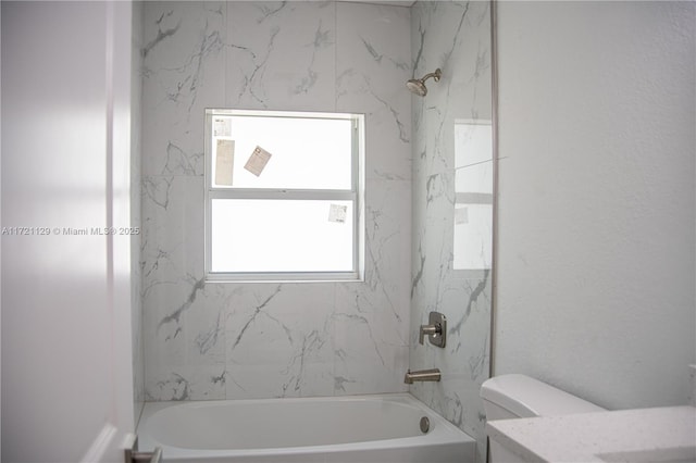 bathroom featuring tiled shower / bath combo and toilet