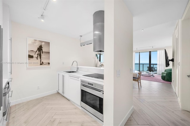 2201 Collins Ave Unit 1128, Miami Beach, FL 33139 - kitchen with stainless steel oven, a sink, rail lighting, black electric stovetop, and baseboards