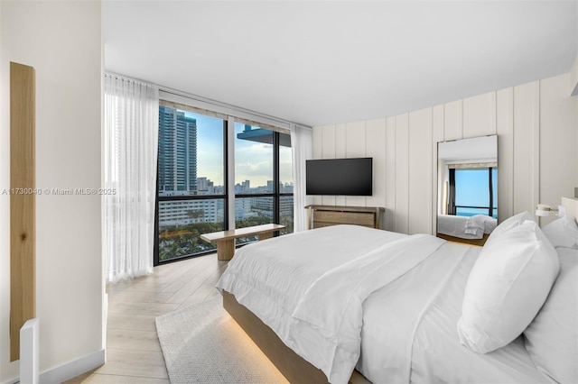 2201 Collins Ave Unit 1128, Miami Beach, FL 33139 - bedroom featuring light wood-type flooring, floor to ceiling windows, and baseboards