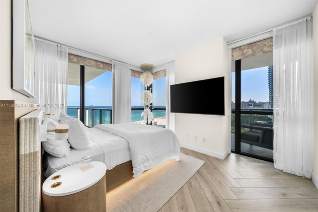 2201 Collins Ave Unit 1128, Miami Beach, FL 33139 - bedroom featuring floor to ceiling windows, access to exterior, wood finished floors, and baseboards