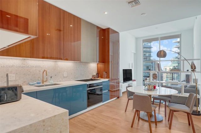 kitchen with sink, backsplash, and light hardwood / wood-style floors