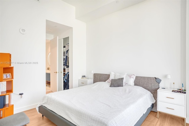 bedroom with a walk in closet, a closet, and light wood-type flooring