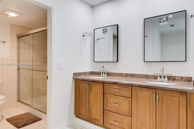 bathroom with tile patterned flooring, vanity, a shower with shower door, and toilet