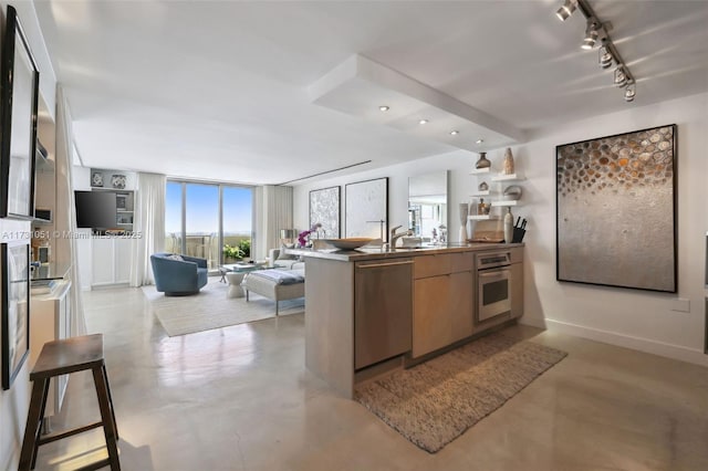 kitchen with a wall of windows, rail lighting, kitchen peninsula, and appliances with stainless steel finishes