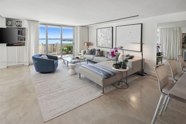 living room featuring concrete flooring, expansive windows, and a water view