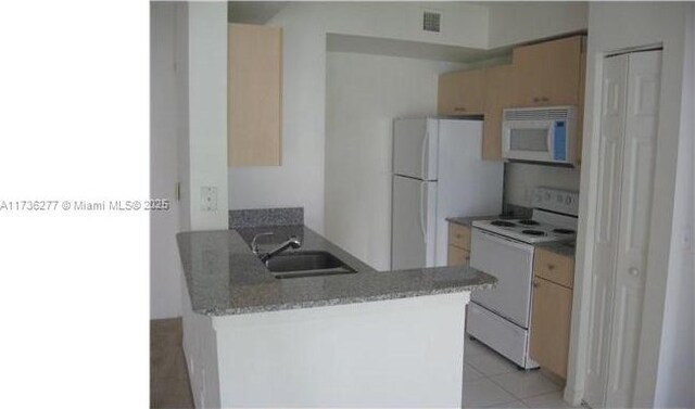 2494 Centergate Dr Unit 103, Miramar, FL 33025 - kitchen with visible vents, a peninsula, white appliances, a sink, and light brown cabinetry