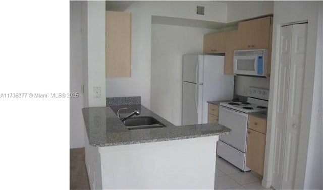 kitchen featuring white appliances, light brown cabinetry, kitchen peninsula, and sink