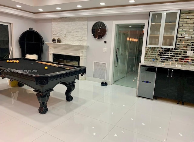 rec room with pool table, ornamental molding, light tile patterned floors, and a fireplace