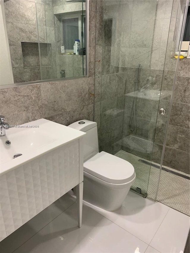 bathroom with tile walls, vanity, a shower with door, and toilet