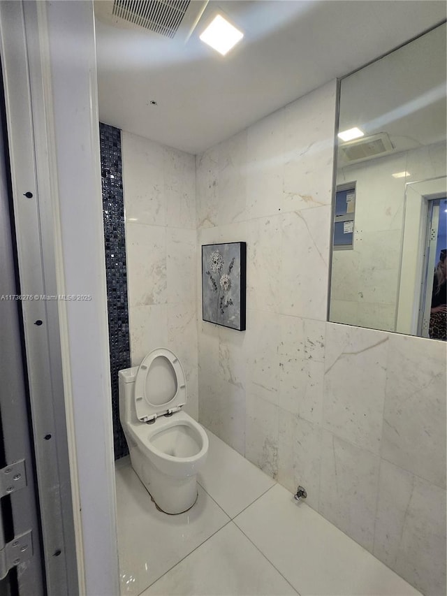 bathroom featuring tile walls, tile patterned floors, and toilet