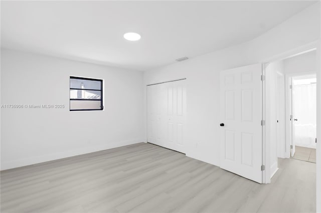 unfurnished bedroom featuring light wood-type flooring and a closet