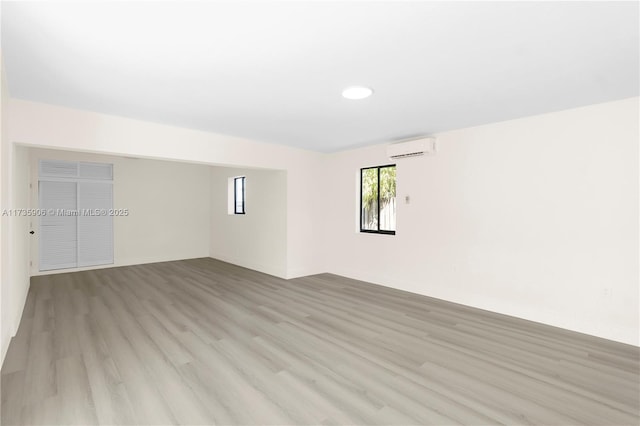 empty room with a wall mounted AC and light hardwood / wood-style flooring