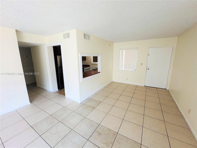 unfurnished room featuring light tile patterned floors and a textured ceiling