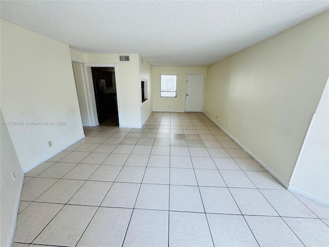 spare room featuring light tile patterned floors and a textured ceiling