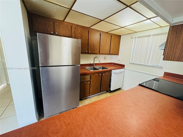 kitchen with extractor fan, sink, stainless steel fridge, white dishwasher, and a drop ceiling