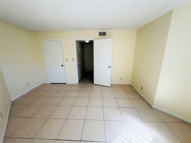 empty room featuring light tile patterned floors and a textured ceiling