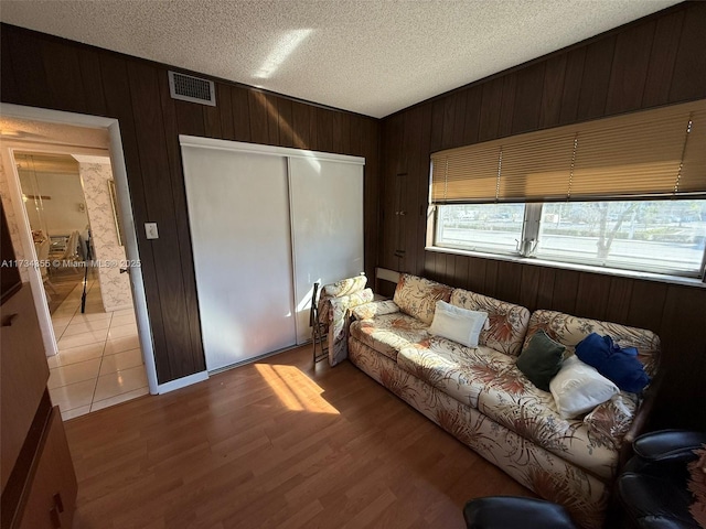 living room with hardwood / wood-style flooring, a textured ceiling, and wood walls