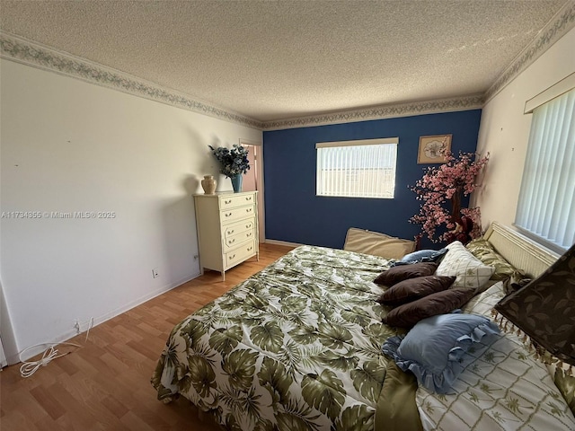 bedroom with ornamental molding, light hardwood / wood-style flooring, and a textured ceiling