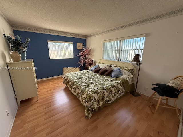 bedroom with multiple windows, a textured ceiling, and light wood-type flooring