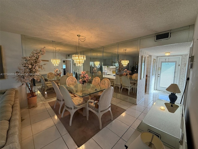 dining space with a chandelier, a textured ceiling, and light tile patterned floors