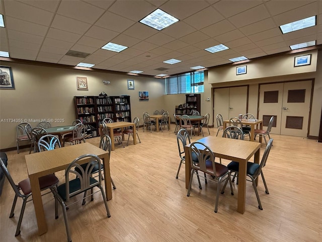 dining space featuring a paneled ceiling, light wood-type flooring, and french doors