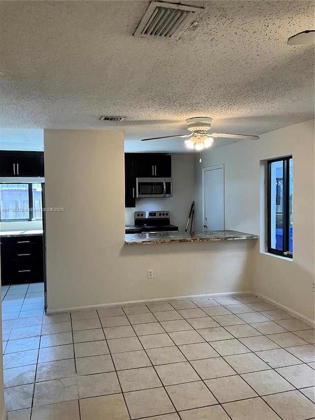 kitchen featuring ceiling fan, stainless steel appliances, a textured ceiling, light tile patterned flooring, and kitchen peninsula