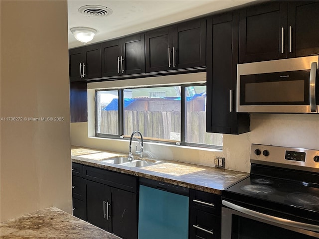 kitchen featuring light stone counters, stainless steel appliances, and sink