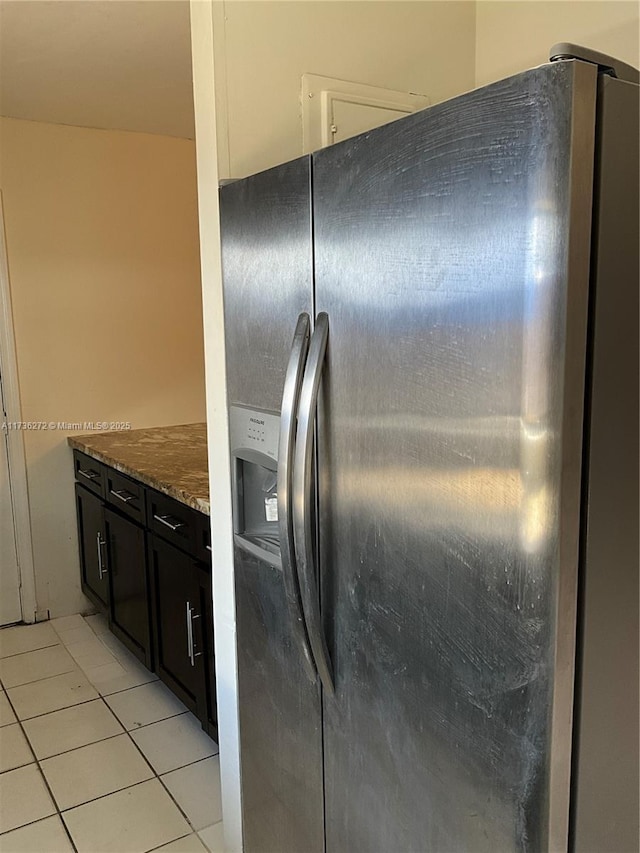 kitchen featuring light tile patterned floors, stainless steel fridge, and dark stone counters