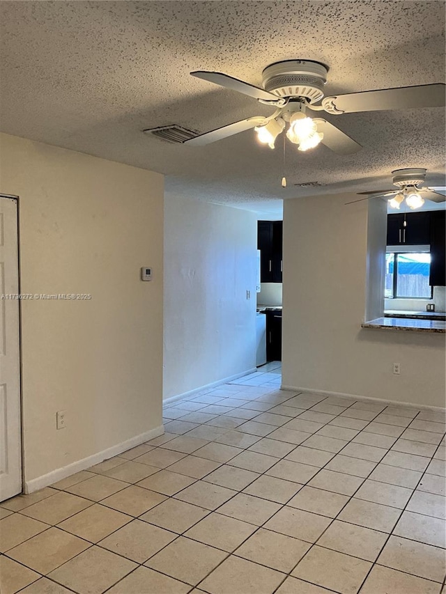 spare room featuring ceiling fan, a textured ceiling, and light tile patterned flooring