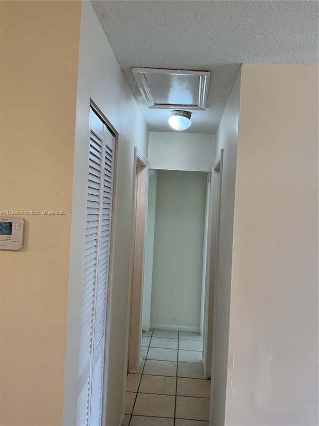 corridor featuring a textured ceiling and light tile patterned flooring