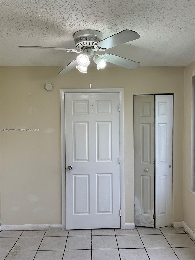 unfurnished bedroom featuring ceiling fan, a textured ceiling, a closet, and light tile patterned floors