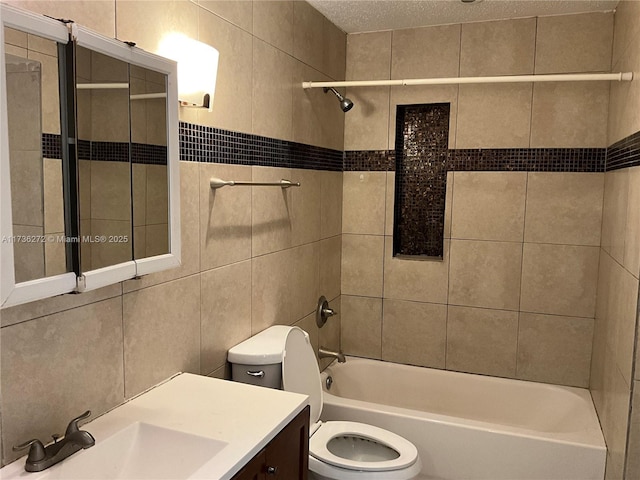 full bathroom featuring vanity, tiled shower / bath, tile walls, and toilet