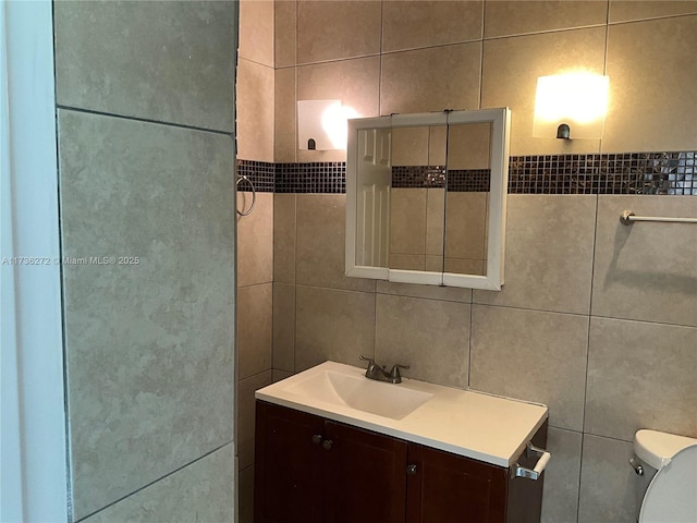 bathroom with vanity, tile walls, and toilet