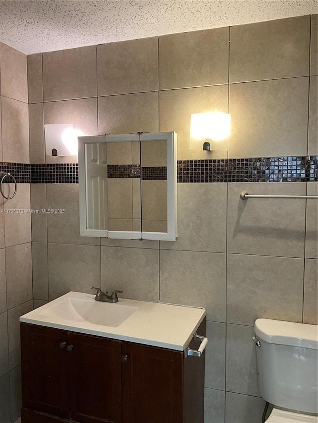 bathroom with vanity, tile walls, and toilet