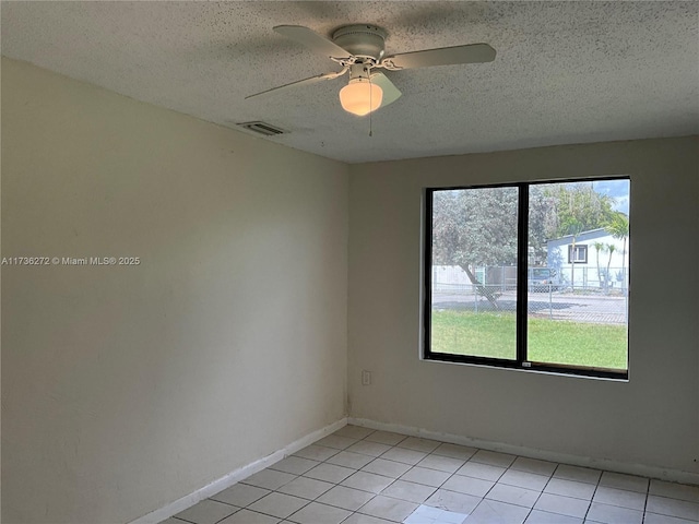 tiled spare room with ceiling fan and a textured ceiling