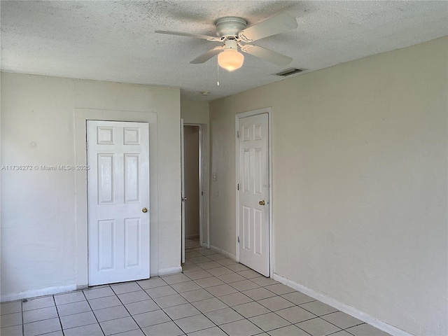 unfurnished bedroom with light tile patterned floors, a textured ceiling, and ceiling fan