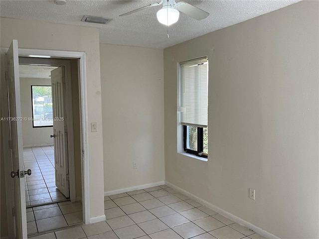 spare room featuring light tile patterned flooring, ceiling fan, and a textured ceiling