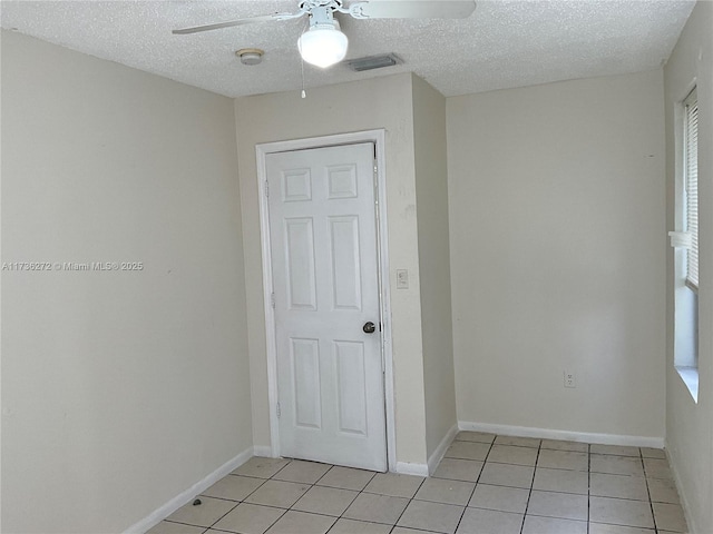 unfurnished room featuring a textured ceiling, ceiling fan, and light tile patterned flooring