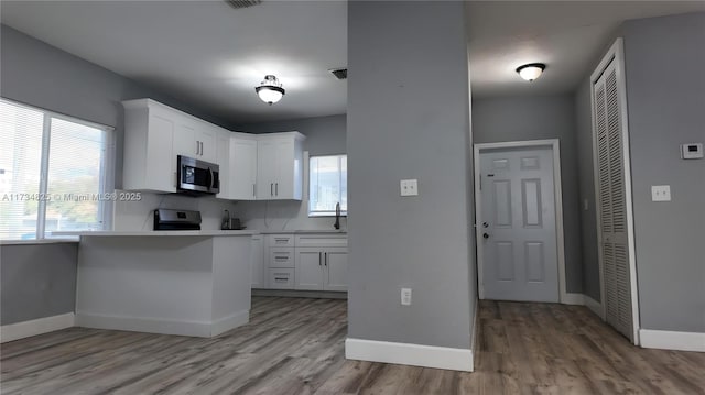 kitchen featuring backsplash, appliances with stainless steel finishes, light hardwood / wood-style flooring, and white cabinets