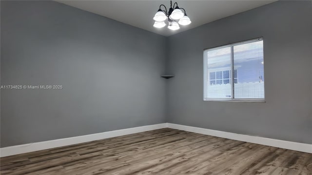 spare room with hardwood / wood-style flooring and an inviting chandelier