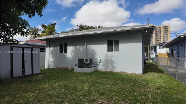 exterior space with central AC unit, a yard, and a storage unit