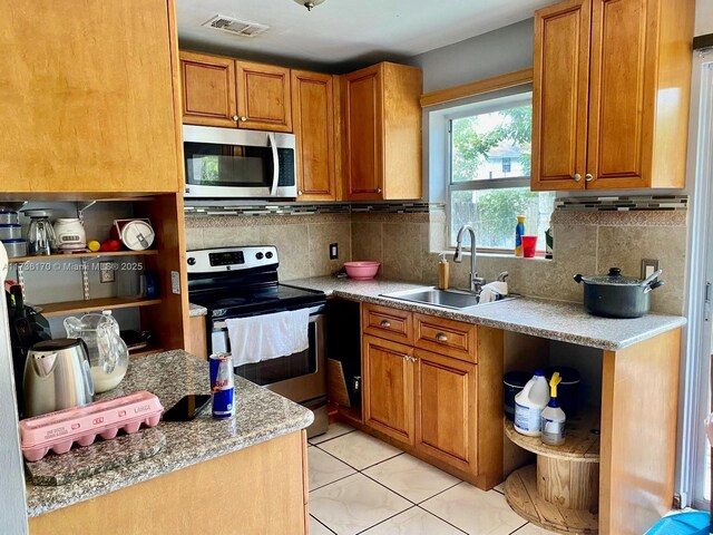 kitchen featuring tasteful backsplash, stainless steel appliances, sink, and light tile patterned floors