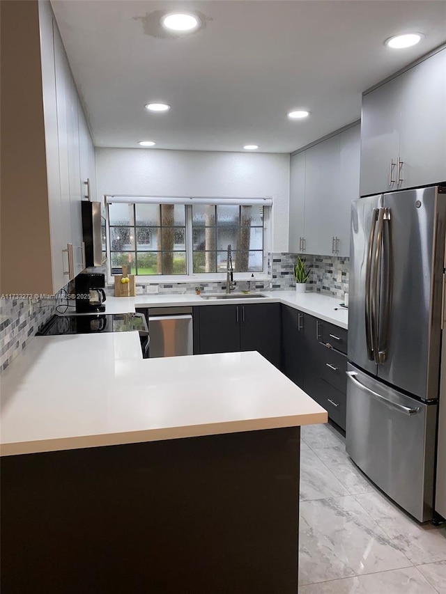 kitchen with tasteful backsplash, stainless steel appliances, kitchen peninsula, and sink