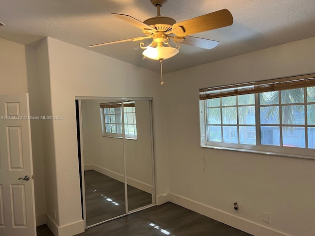 unfurnished bedroom with dark wood-type flooring, vaulted ceiling, a closet, and a textured ceiling