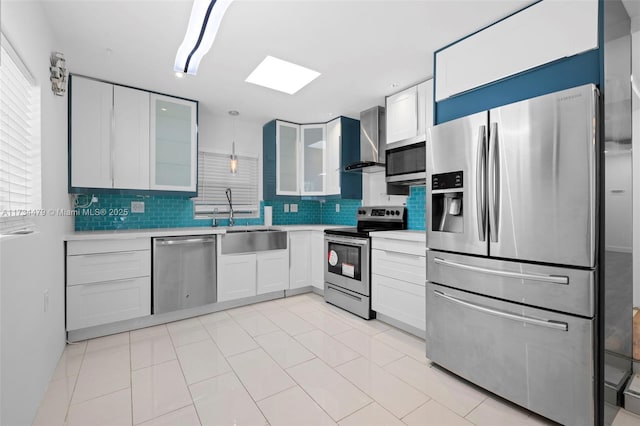 kitchen featuring appliances with stainless steel finishes, decorative light fixtures, sink, white cabinets, and wall chimney exhaust hood