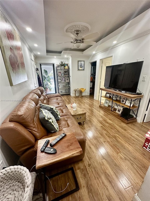 living room with hardwood / wood-style flooring, a raised ceiling, and ceiling fan