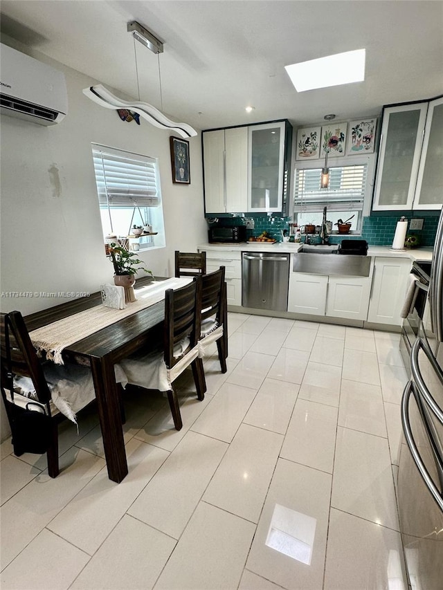 kitchen with decorative light fixtures, white cabinetry, dishwasher, a wall mounted AC, and decorative backsplash