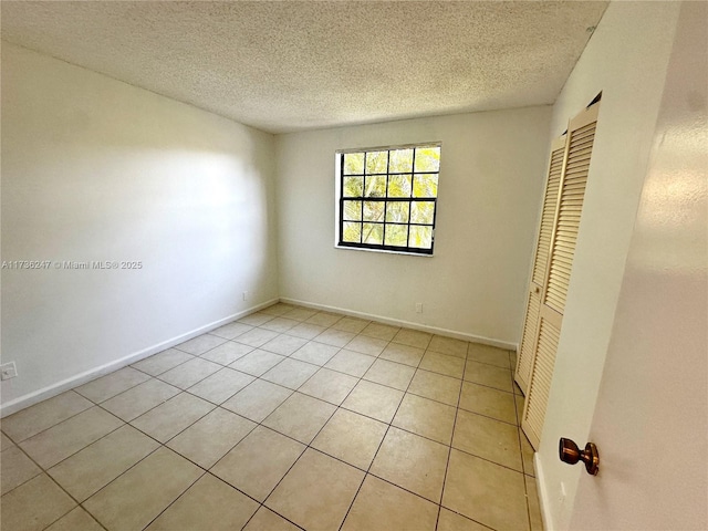 unfurnished bedroom featuring light tile patterned flooring, a textured ceiling, and a closet