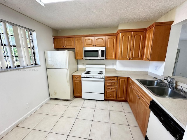 kitchen with white appliances, sink, a textured ceiling, and light tile patterned floors